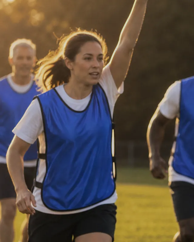 An adult player calling for the ball in a blue SportsRepublik pinnie worn over a t-shirt at an evening scrimmage